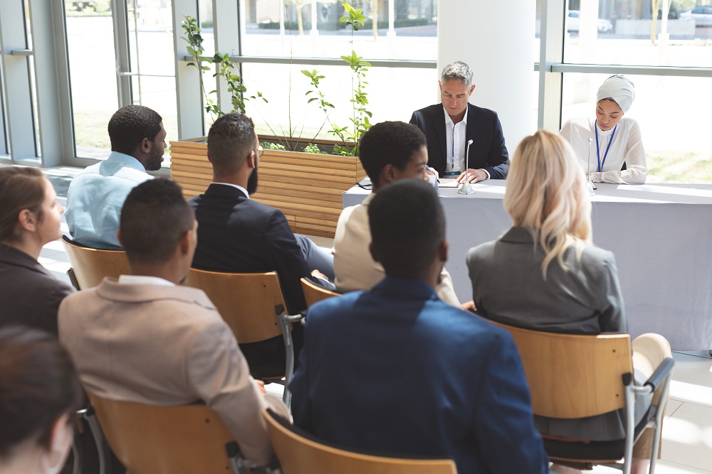 Menschen, die auf Stühlen sitzen und an einer Konferenz teilnehmen