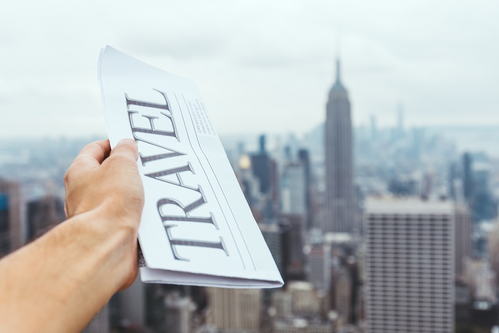 Zeitung mit "Reise" darauf, vor einer Skyline.