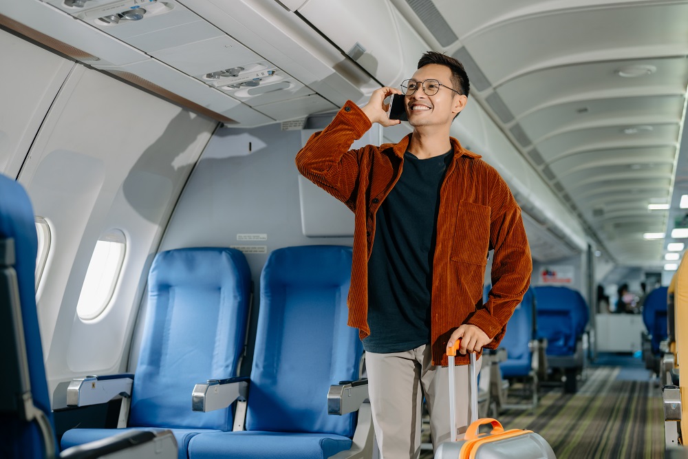 Business traveler on the phone looking for his seat on the airplane