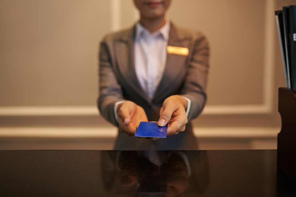 Hotel receptionist with hotel loyalty card in hands