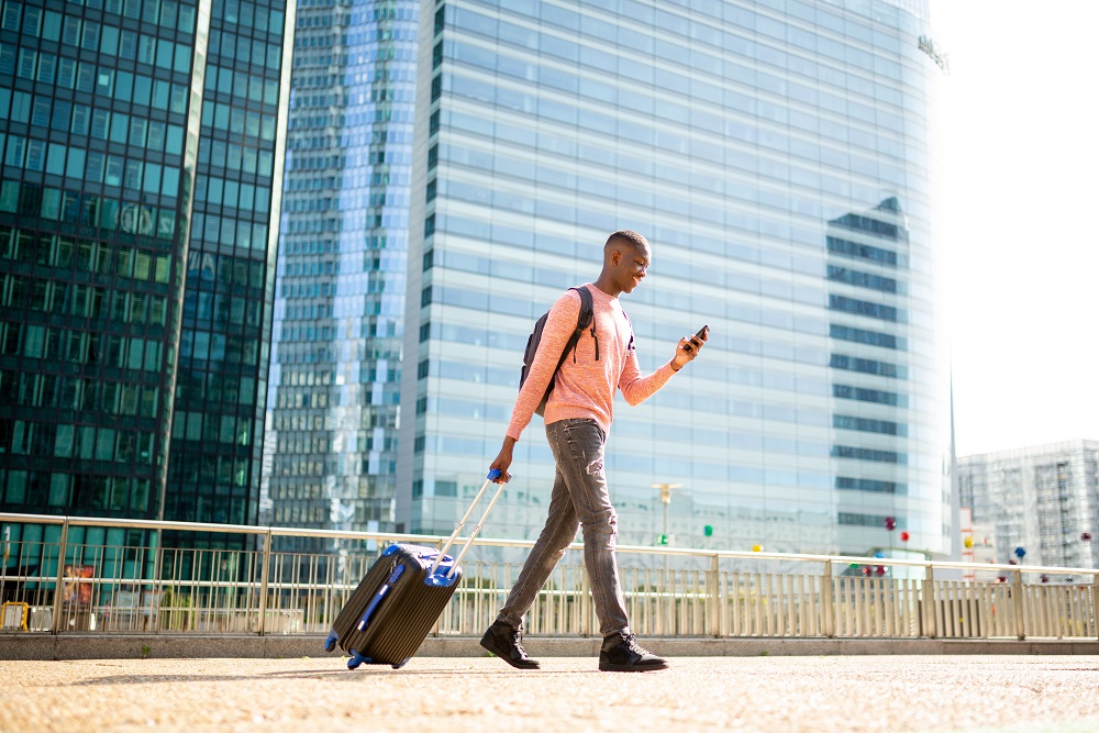 Happy business traveler walking with suitcase in city