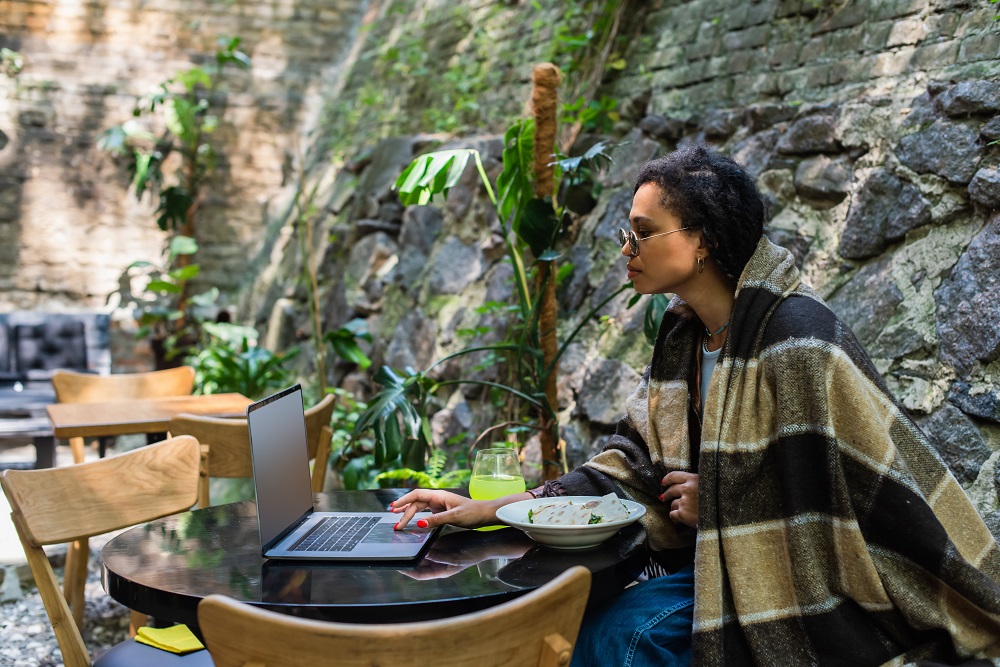 Girl working remotely with a stone wall behind her