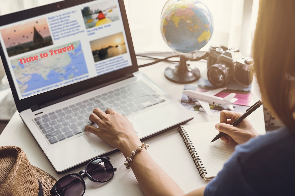 Woman booking travel with laptop and writing on notepad