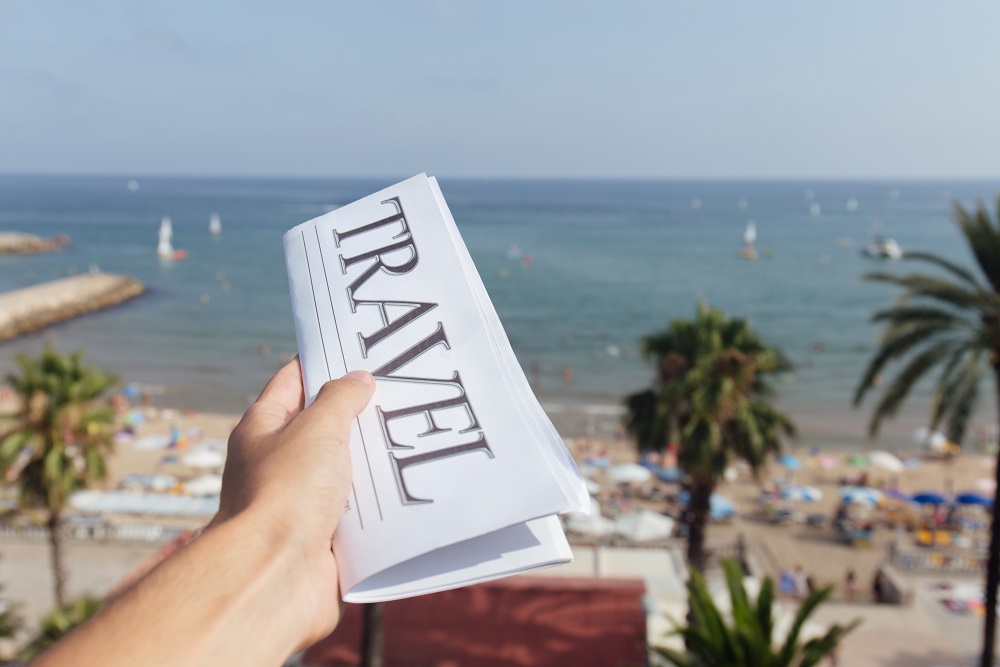 Newspaper with travel written on it in front of seaview