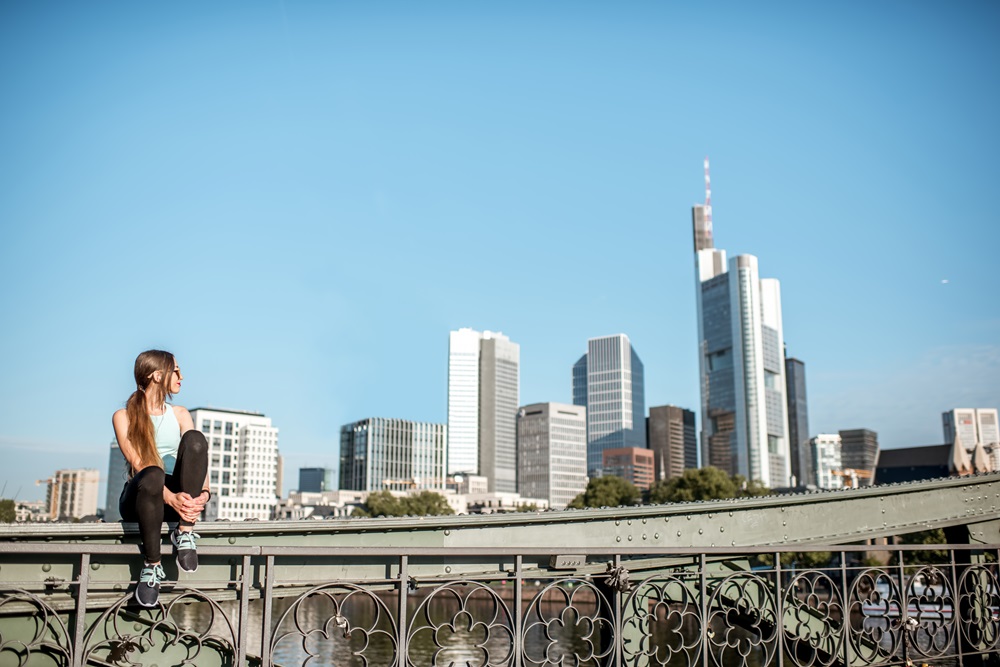 Woman sitting on bridge with Frankfurt skyline in background