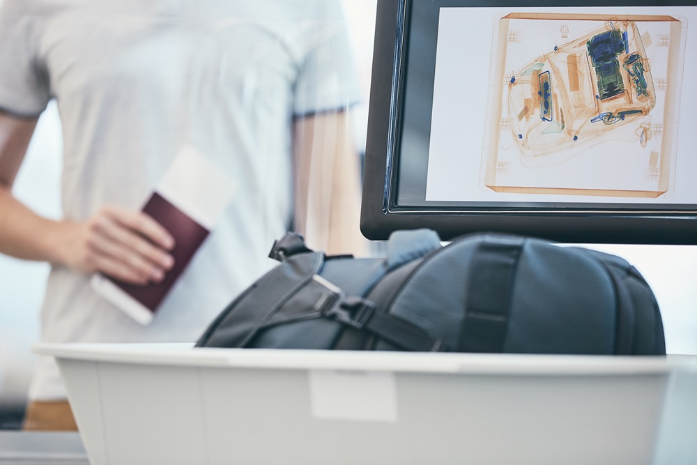 business traveler waiting for luggage to be scanned at airport security